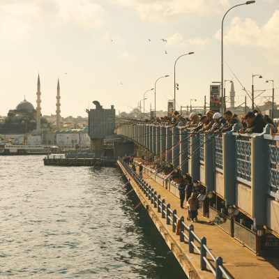 Fishermen on Galata bridge in Istanbul with cityscape and Galata tower on background.